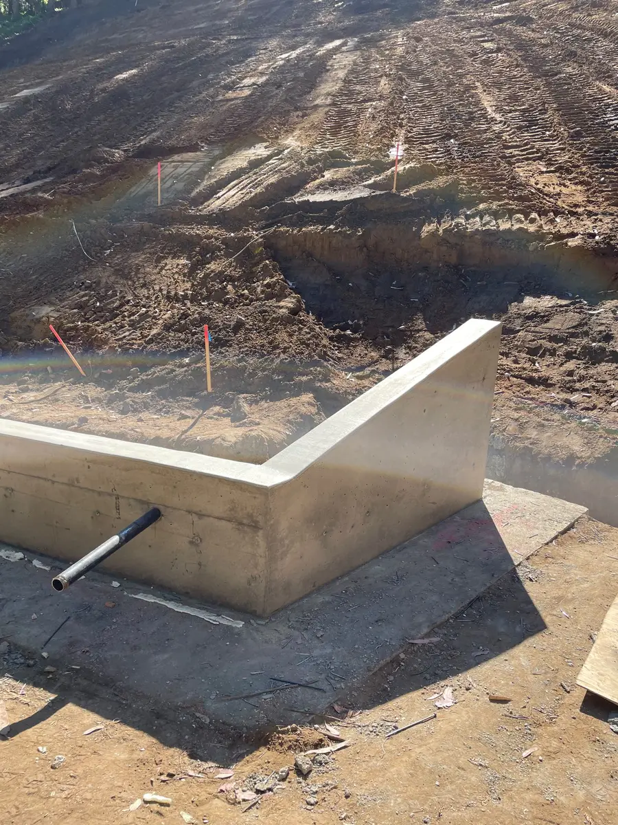 Poured concrete footing corner with a drain sleeve in place.