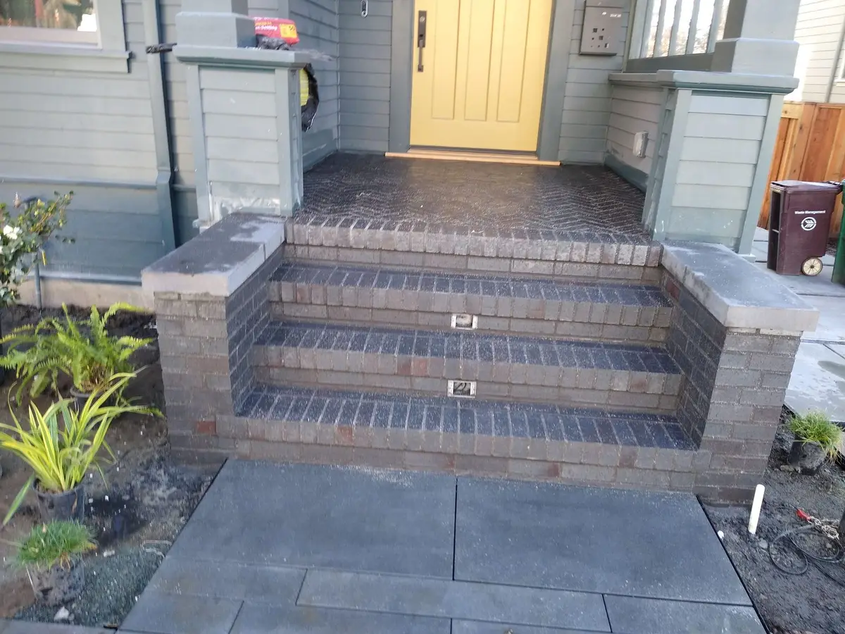 Brick paver entry steps with masonry side walls and a bluestone landing at a residence.