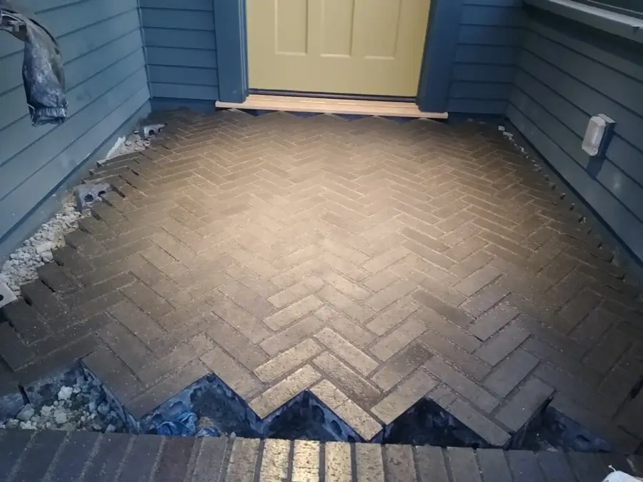 Herringbone brick pavers being set on the landing in front of an entry door.