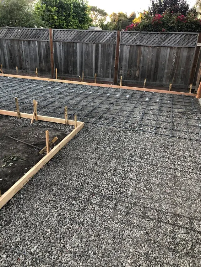 Reinforcing steel tied over base rock inside the forms of a backyard slab.